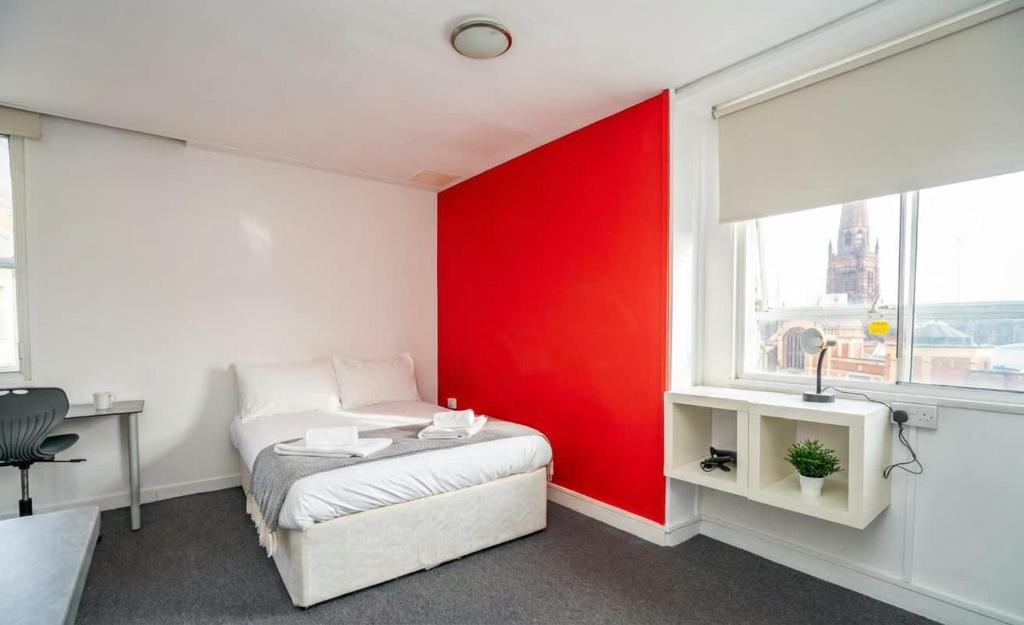 a bedroom with a red accent wall and a bed at Spacious & Bright Central Coventry Budget Studio in Coventry
