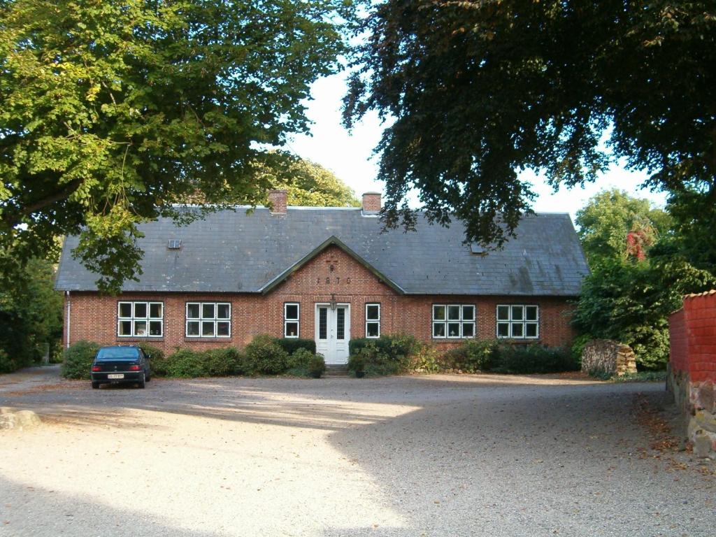 a red brick house with a car parked in front of it at Vejlø Skole - Degnegaarden in Næstved