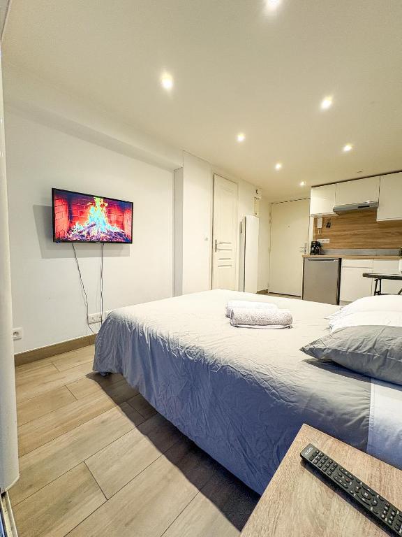 a bedroom with two beds and a tv on the wall at Studio - Centre Ville in Sartrouville