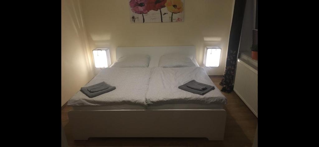 a white bed in a room with two windows at Pension am Markt Luckenwalde in Luckenwalde