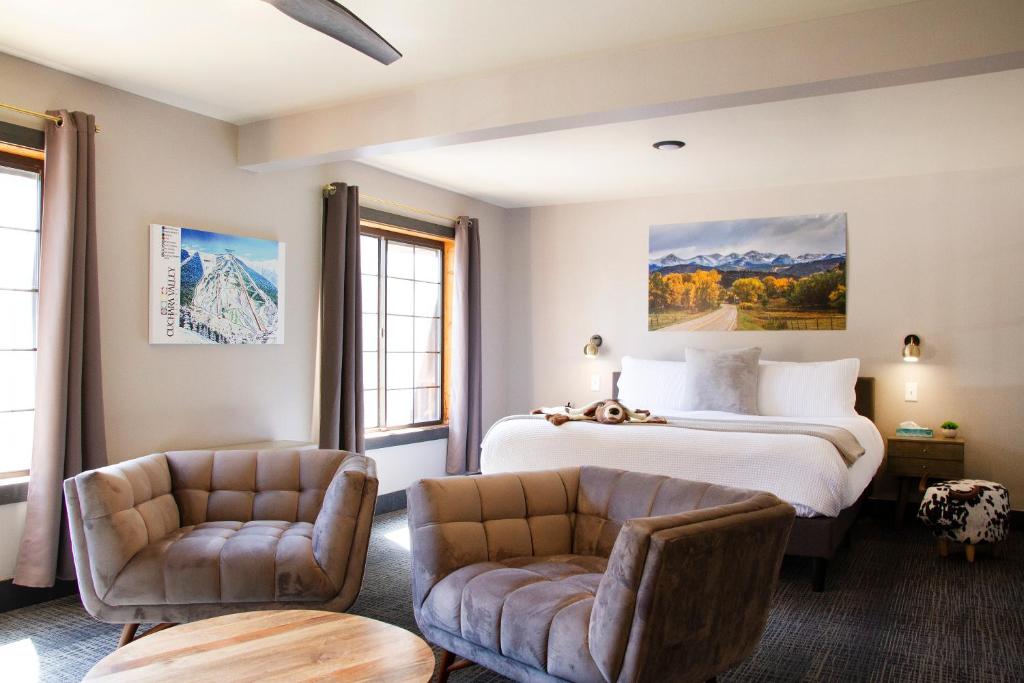 a hotel room with a bed and two chairs at Cuchara Lokal in La Veta