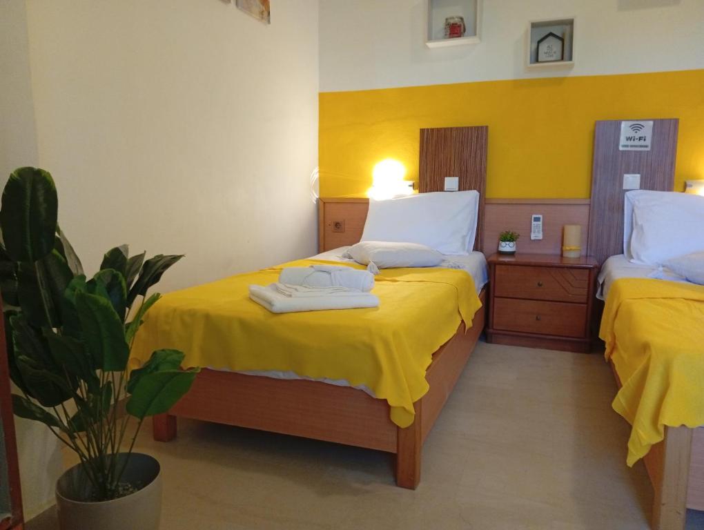 a bedroom with two beds with yellow sheets and a plant at on the STRIP apartment 4 in Kavos