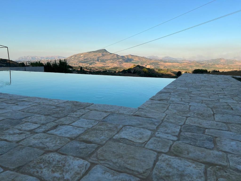 a pool of water with mountains in the background at RossoScirì in Calatafimi