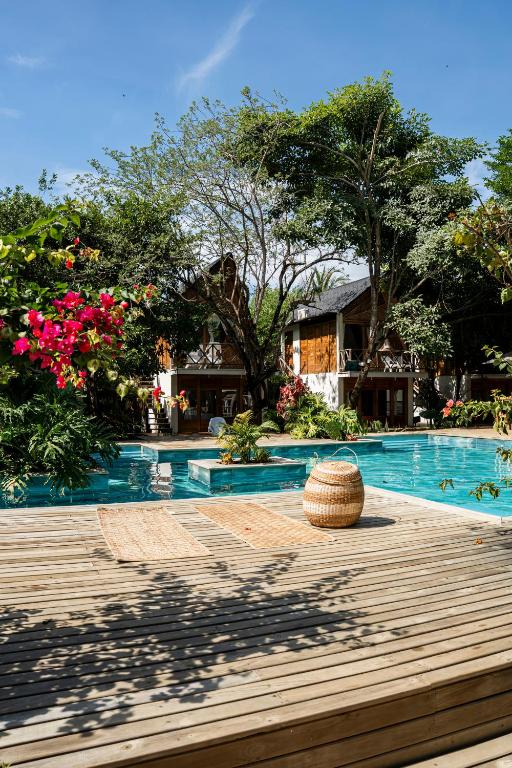 a swimming pool with a wooden deck and flowers at Sambe Manglar in Moñitos