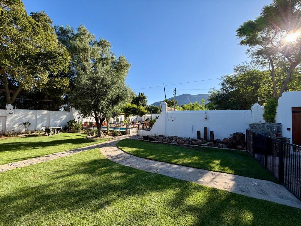 a yard with a white fence and green grass at Far Far Away Guesthouse - 4-star Luxury Karoo Escape with Garden, Pool & Personal Touch in Graaff-Reinet