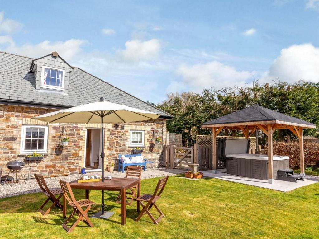 a garden with a table and an umbrella and a grill at 2 Bed in Launceston oc-41992 in Saint Giles on the Heath