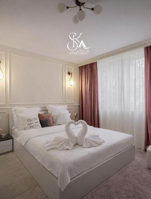 a bedroom with a white bed with two white hearts on it at Sika DeLuxe Apartment - cazare Arad - self check-in in Arad