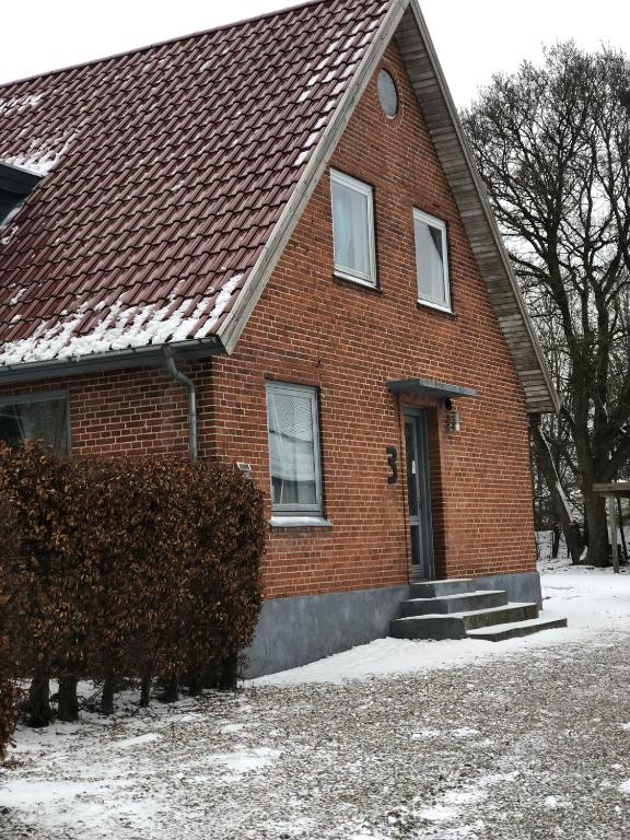 a red brick house with a brown roof at Huset i Hammelev in Vojens