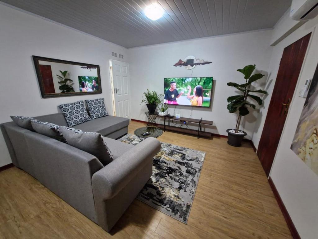 a living room with a couch and a tv at Gaborone Platinum Self Catering in Gaborone
