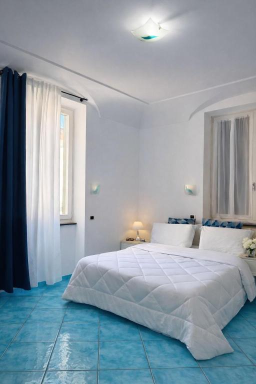 a white bedroom with a large white bed and a window at In centro - De Jusola apartment in Maiori