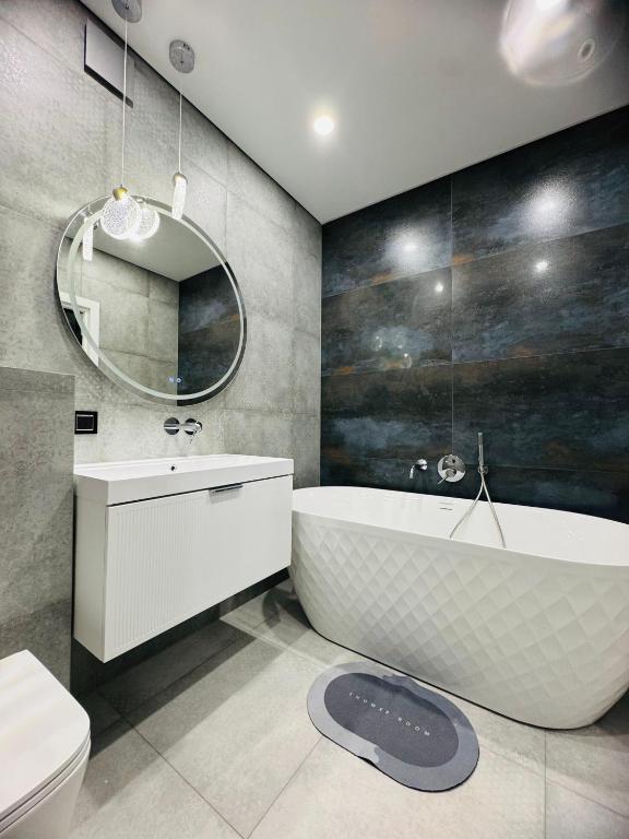 a bathroom with a tub and a toilet and a mirror at Перлина Люкс in Khmelnytskyi