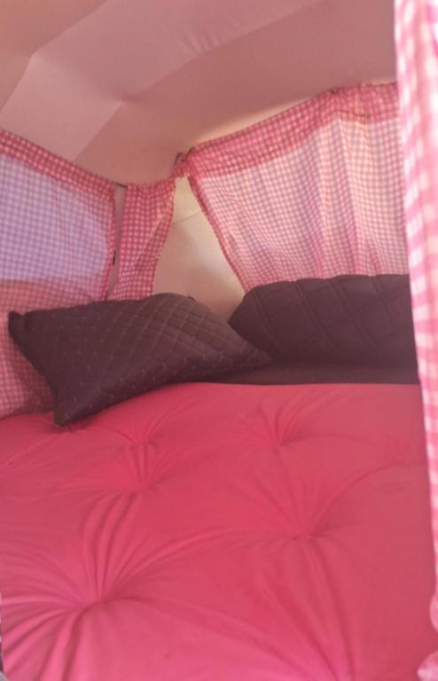 a pink bed with black pillows on it at Fusca Home in Piedade