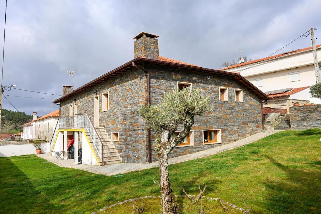 a large stone house with a staircase in a yard at Casa do Olival in Macedo de Cavaleiros
