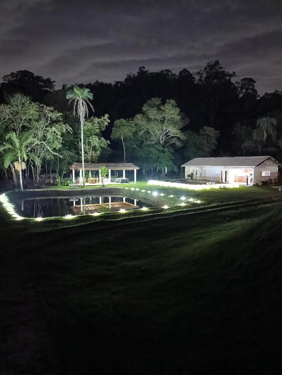 a house at night with a pond and a building at Chácara Paraíso in Itupeva