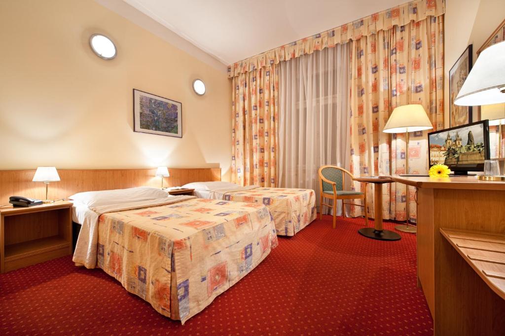 プラハにあるアロンのベッド2台とデスクが備わるホテルルームです。