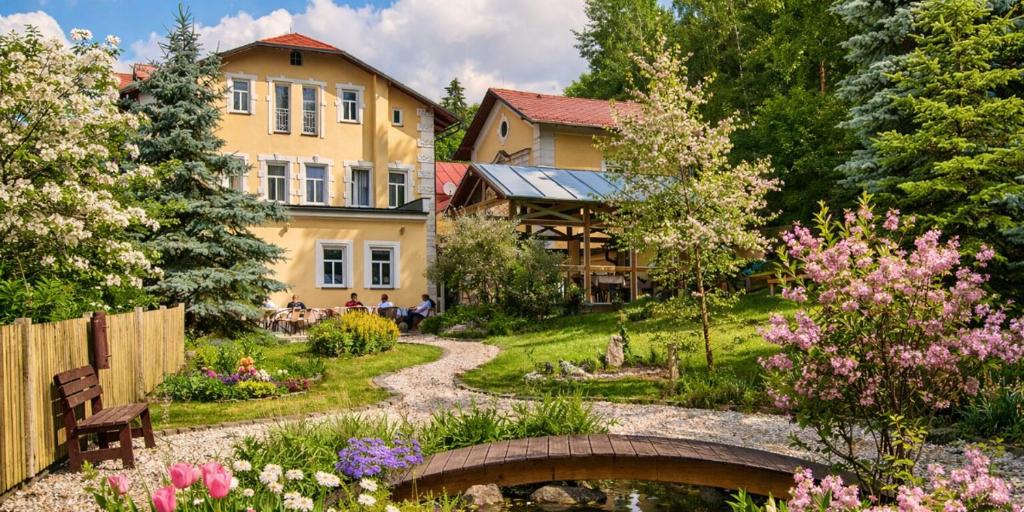 a garden with a bridge and a house at Boutique Hotel SwissHouse in Mariánské Lázně