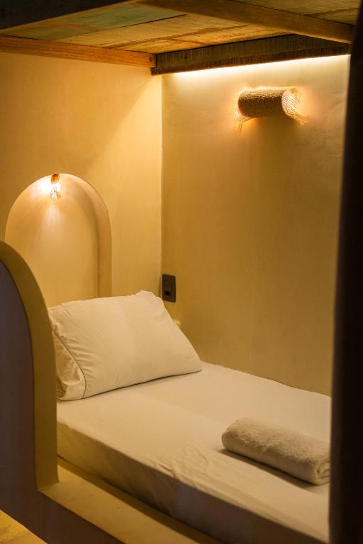 a bed in a room with a light on the wall at Hostel Tainha Caraíva in Caraíva