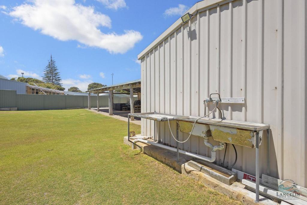 a side of a building with a field next to it at Sea Chain in Lancelin