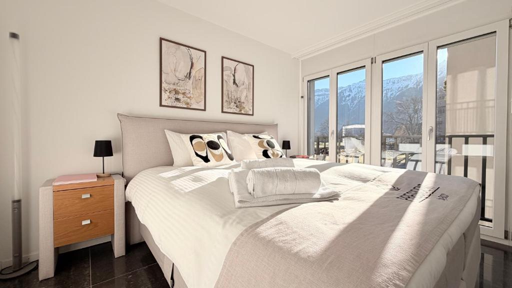 a bedroom with a large white bed and windows at Center Park Apartment in Interlaken
