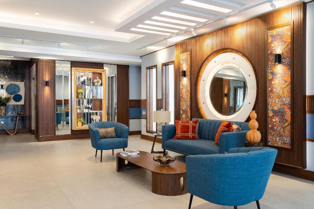 a living room with blue chairs and a mirror at Shalom Suites by Yellowkey in Santo Domingo