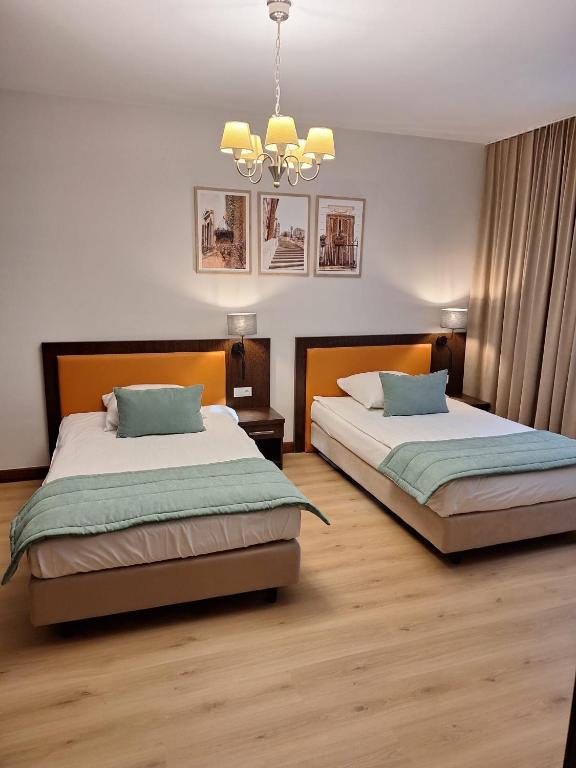 a bedroom with two beds and a chandelier at Pokoje De Luxe Figaro in Płock