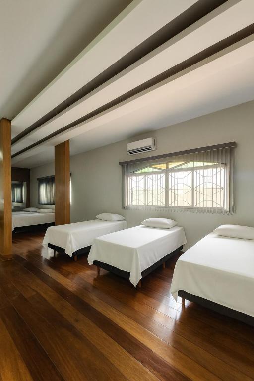 a large room with three beds and a window at Studio para 7 pessoas com Ar Condicionado e 2 Garagem in Uberlândia