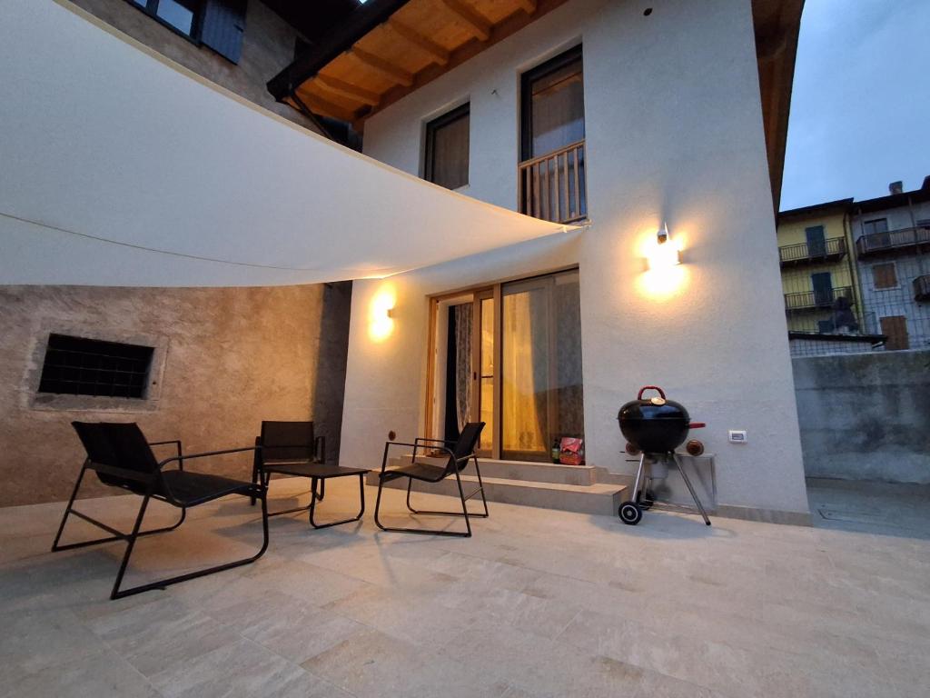 a patio with chairs and a table and a grill at Chalet La coccola di Lulù in Molina di Ledro