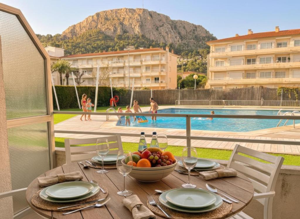 Ein Tisch mit einer Obstschale auf einem Balkon mit Pool in der Unterkunft El Foraió in L'Estartit