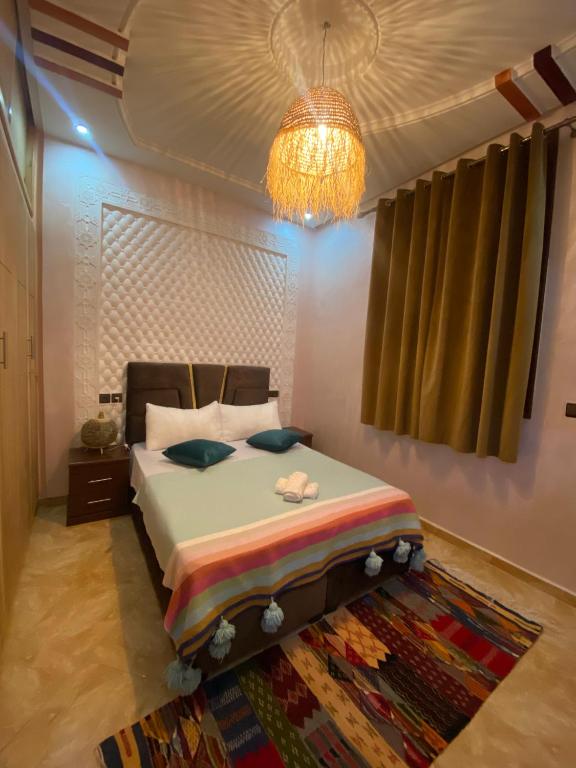 a bedroom with a bed and a chandelier at maison de bonheur 2 in Tafraout