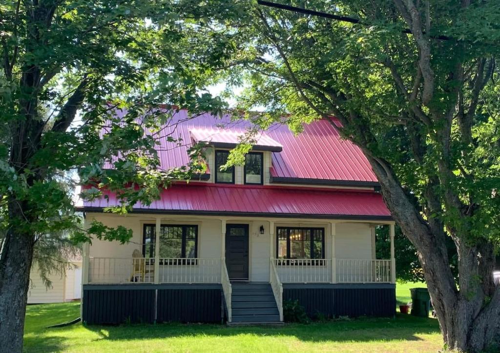 a house with a red roof and trees at Chalet l'Intemporel - St Lawrence View in Notre-Dame-du-Portage