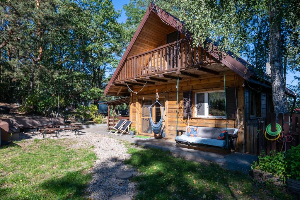 a log cabin with a porch and a swing at Dream Forest Cabin -dom w lesie pod Warszawą in Warsaw