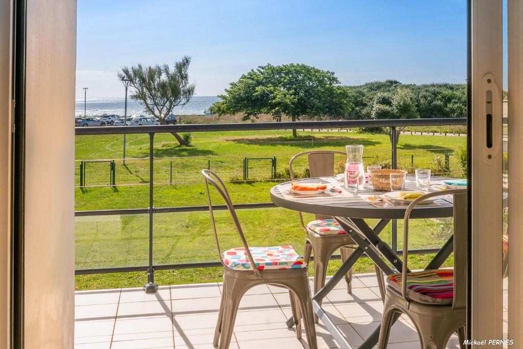a table and chairs on a balcony with a view of a field at REF 321 - LARMOR PLAGE appartement type 3 vue mer in Larmor-Plage