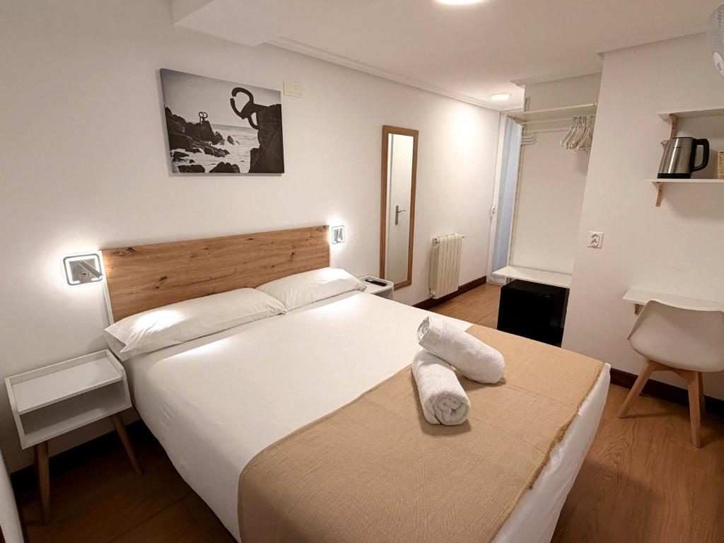 a bedroom with a large white bed with towels on it at Pensión Santa Clara in San Sebastián