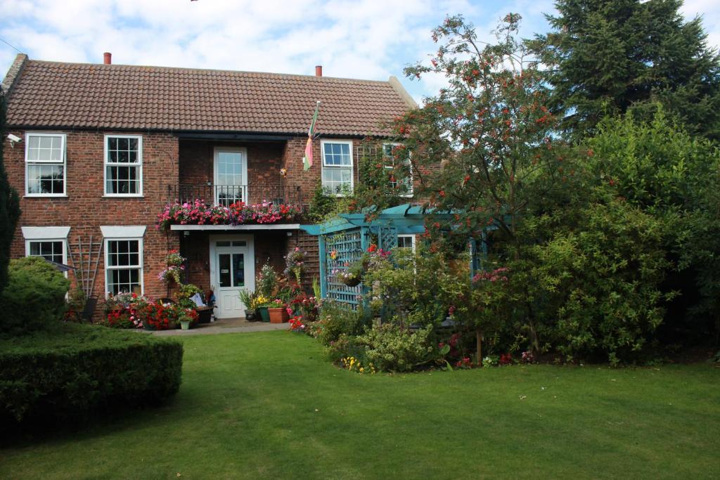 una casa de ladrillo con flores en el patio en The Old Manor at North Somercotes, en North Somercotes