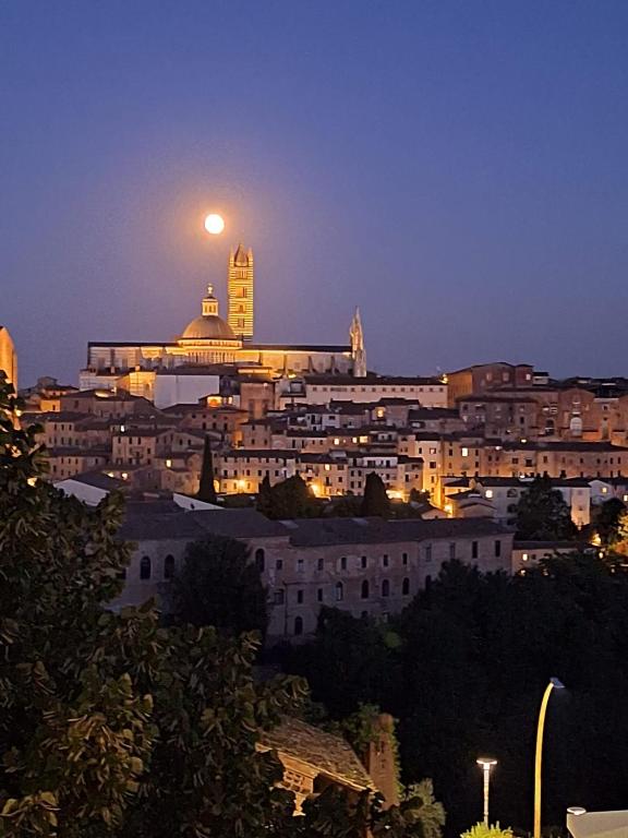 a view of a city at night with a moon at B&B Siena Le Grondaie in Siena