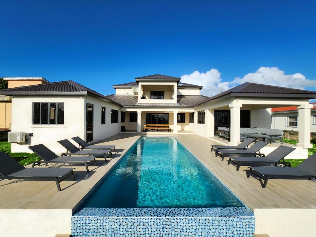 a villa with a swimming pool in front of a house at Mullins Bay View - 4 Bed - Sea View, Infinity Pool in Saint Peter