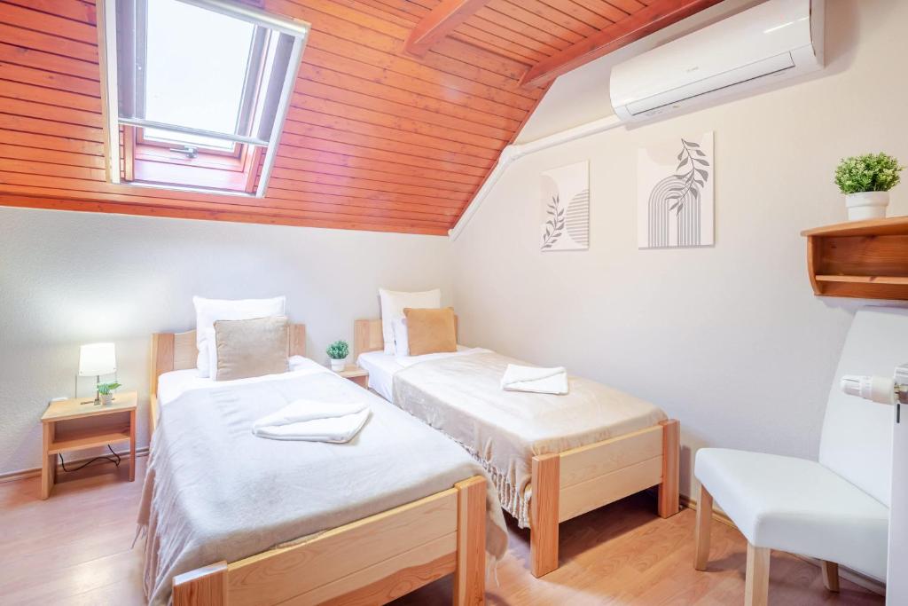 two beds in a room with a wooden ceiling at Easy Sleep - Comfy Stay in Soltvadkert