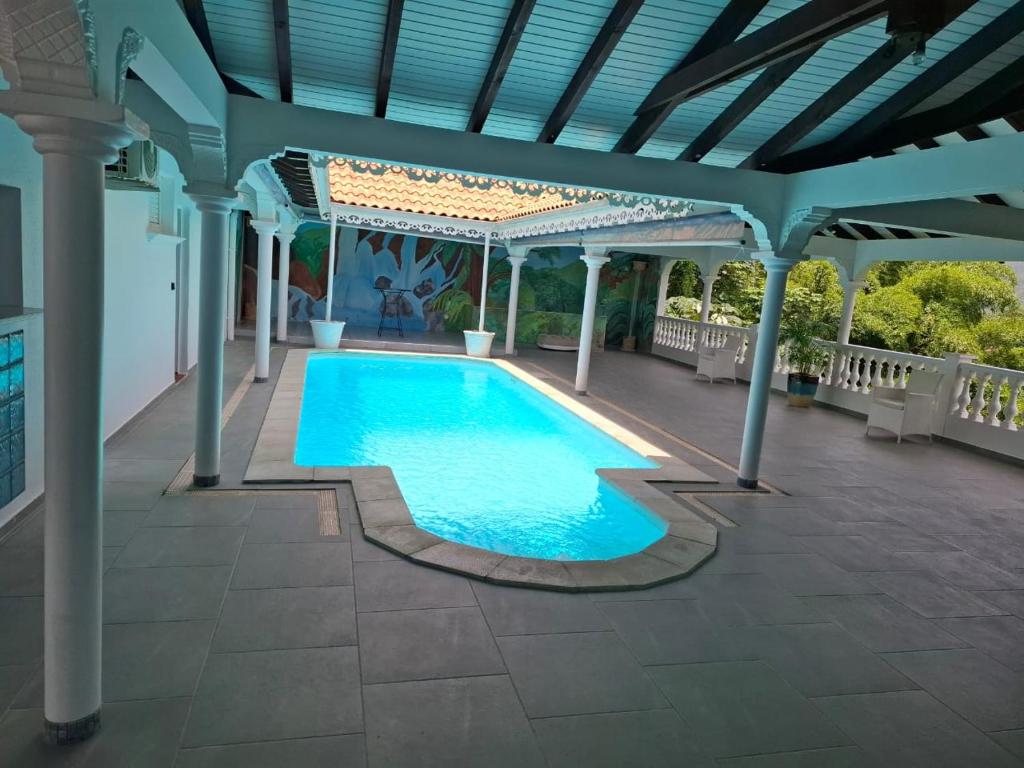 a swimming pool with a pergola and a swimming poolvisor at Le Chalet d'Ajoupa in LʼAjoupa-Bouillon