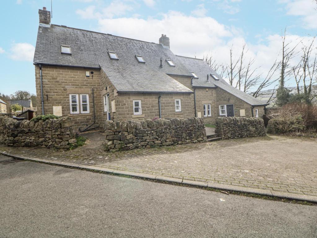 a large brick house with a stone wall at Win Hill View in Bamford