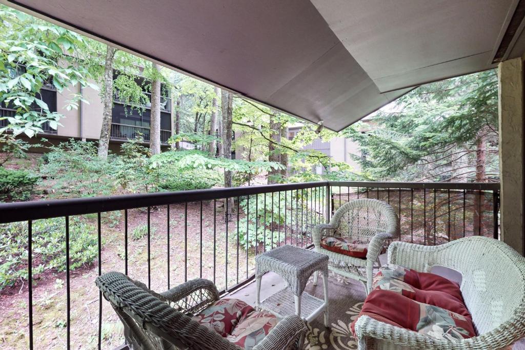a balcony with wicker chairs and a table on a porch at Charming Condo Sleeps 6 Shared Pool Gym Fireplace in Gatlinburg