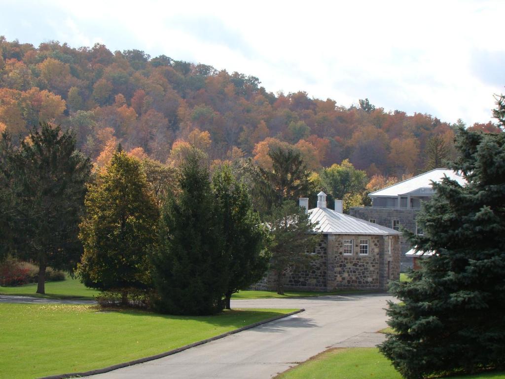 een gebouw voor een berg met bomen bij Auberge de l'Abbaye d'Oka in Oka