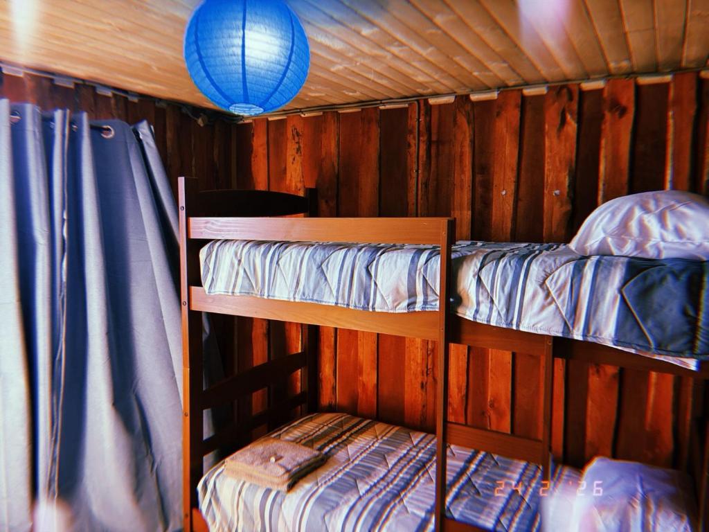 two bunk beds in a wooden cabin with a blue light at MiraMar Casa Azul in Puerto Saavedra