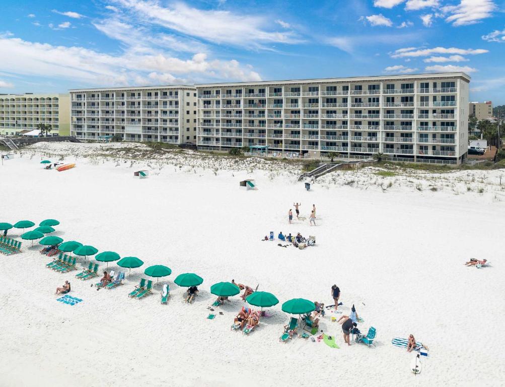 a beach with chairs and green umbrellas and a building at Gulf Dunes 106 Gulf Front condo in Fort Walton Beach