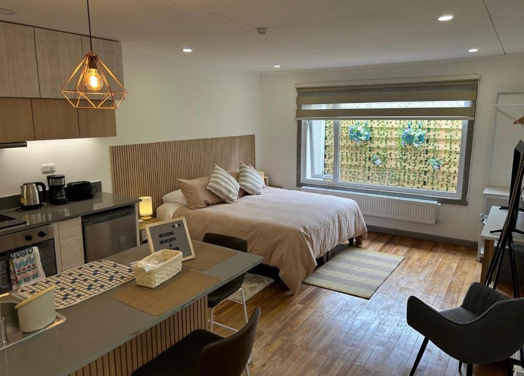 a bedroom with a bed and a desk and a kitchen at Next Door in Punta Arenas