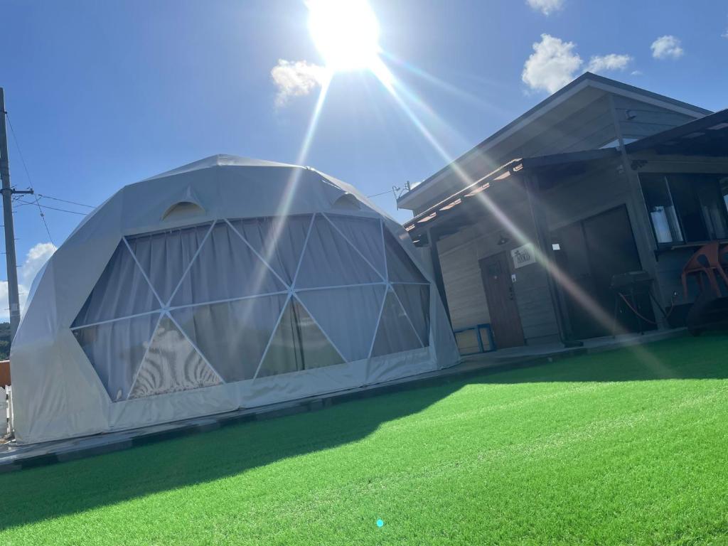 a dome tent on a lawn in front of a house at glamping base YOLO in Nakijin