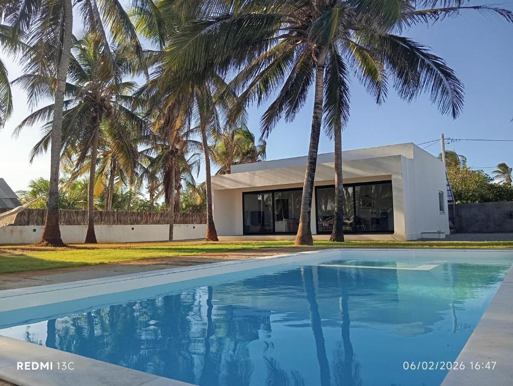 a swimming pool in front of a building with palm trees at Casa Olivia - Eureka in Atins