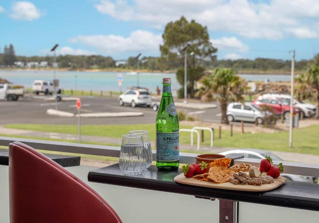 a table with a bottle of beer and a plate of food at Reddall Waterside Stay in Lake Illawarra