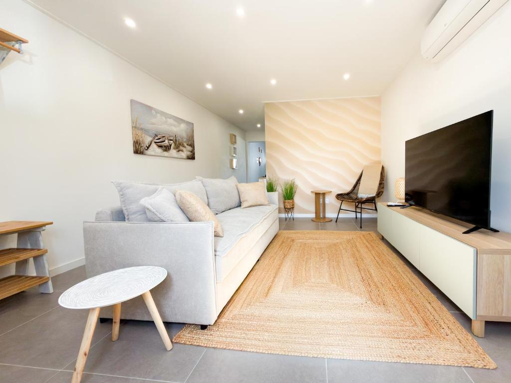 a living room with a white couch and a flat screen tv at Alma de Areia - Alma Nossa in Montijo