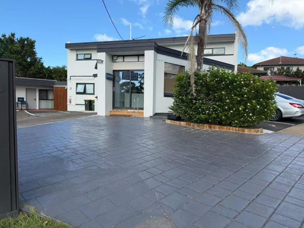 a white house with a palm tree and a driveway at Aspley Motor Inn in Brisbane