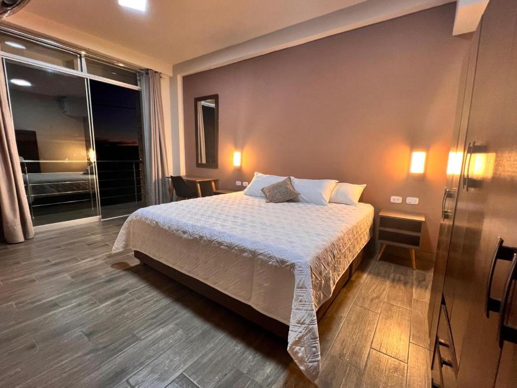 a bedroom with a bed and a large window at La Posada del Pastor in Tarapoto